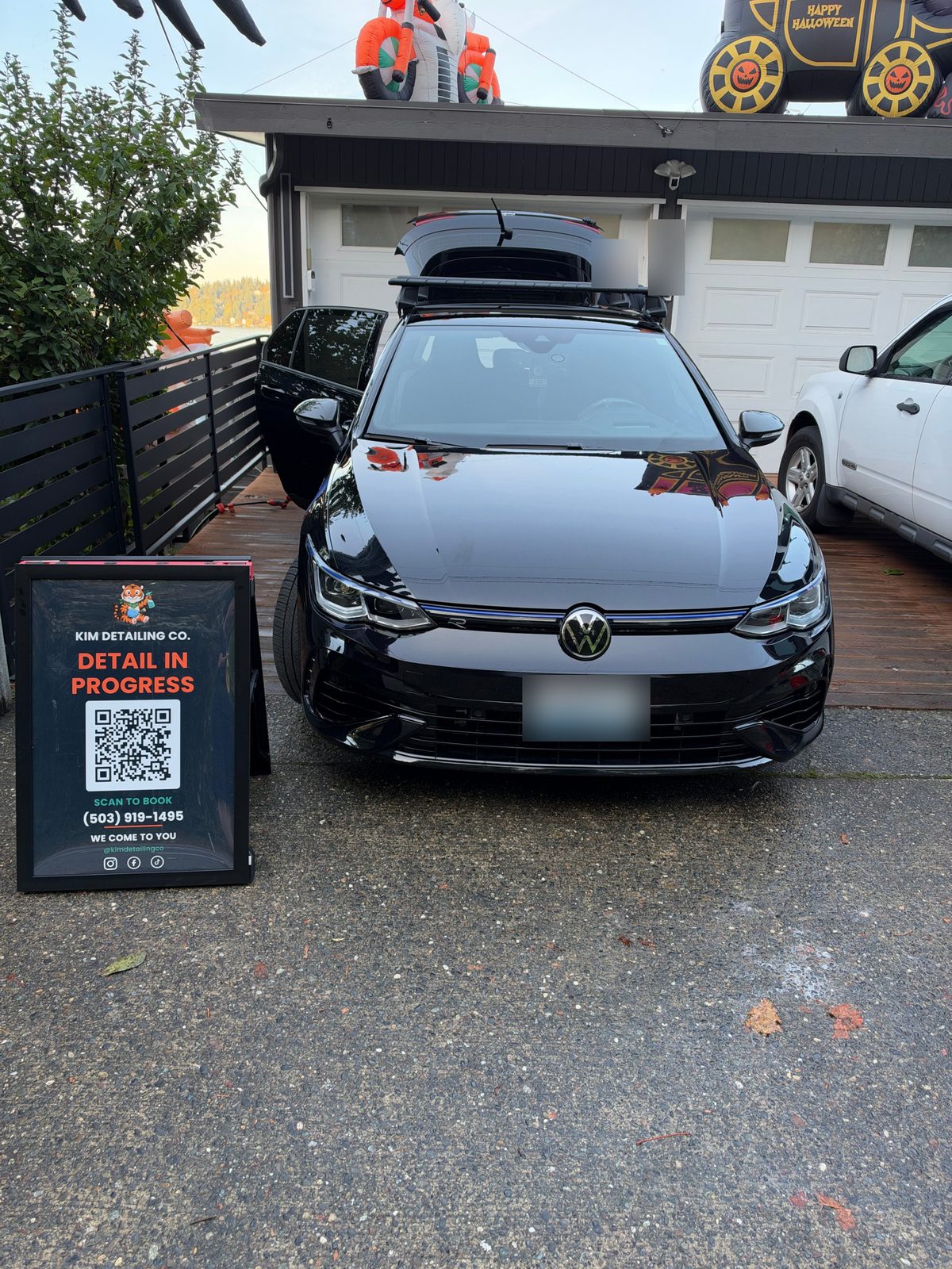 Black VW Golf R after a hand wash and ceramic sealant, with a Kim Detailing Co. sign in the driveway